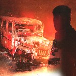 A bus that was burned with a man looking at it