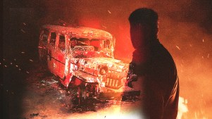 A bus that was burned with a man looking at it