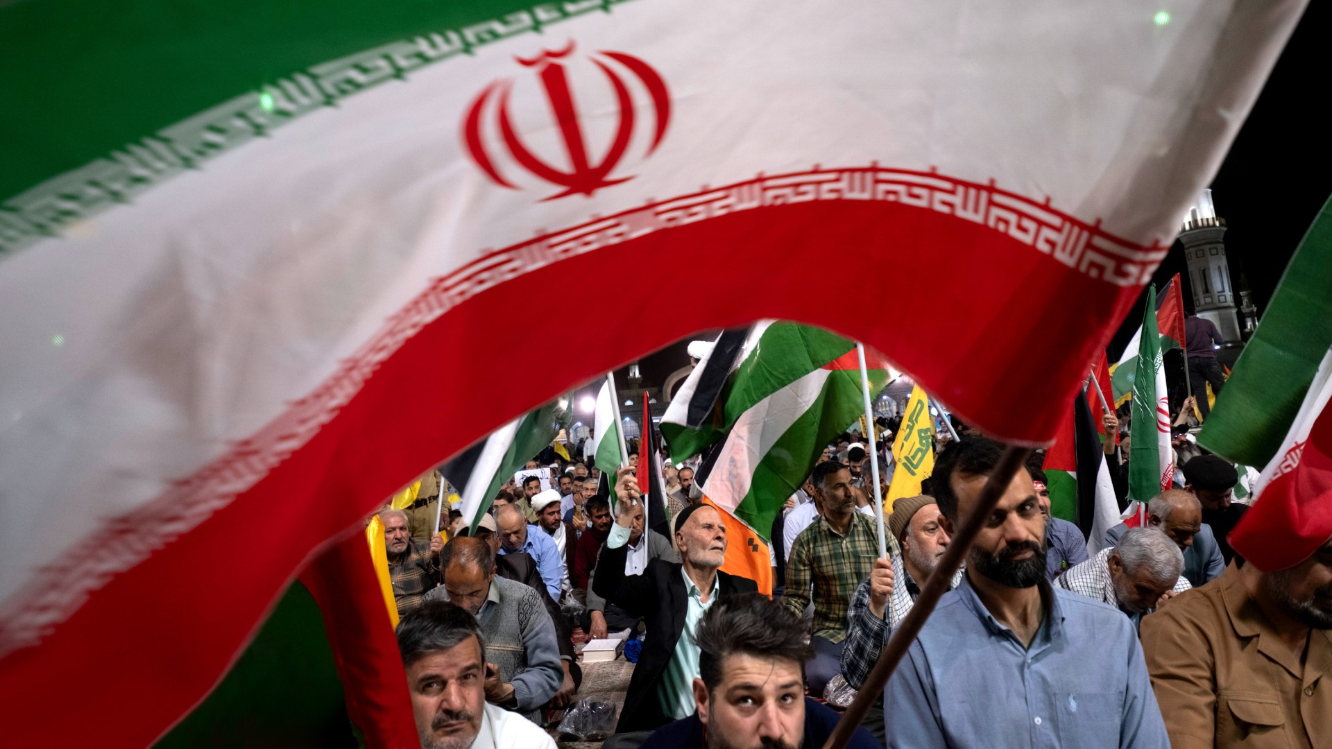 An Iranian protester waves an Iranian flag while participating in a multinational rally at the holy mosque of Jamkara.