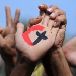 A cross representing Christianity and a crescent representing Islam painted on the palm of a demonstrator during a rally in support of national unity in Egypt.