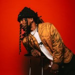nobigdyl. leaning on a stool in front of a red background