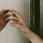 A hand reaching towards its reflection in the mirror