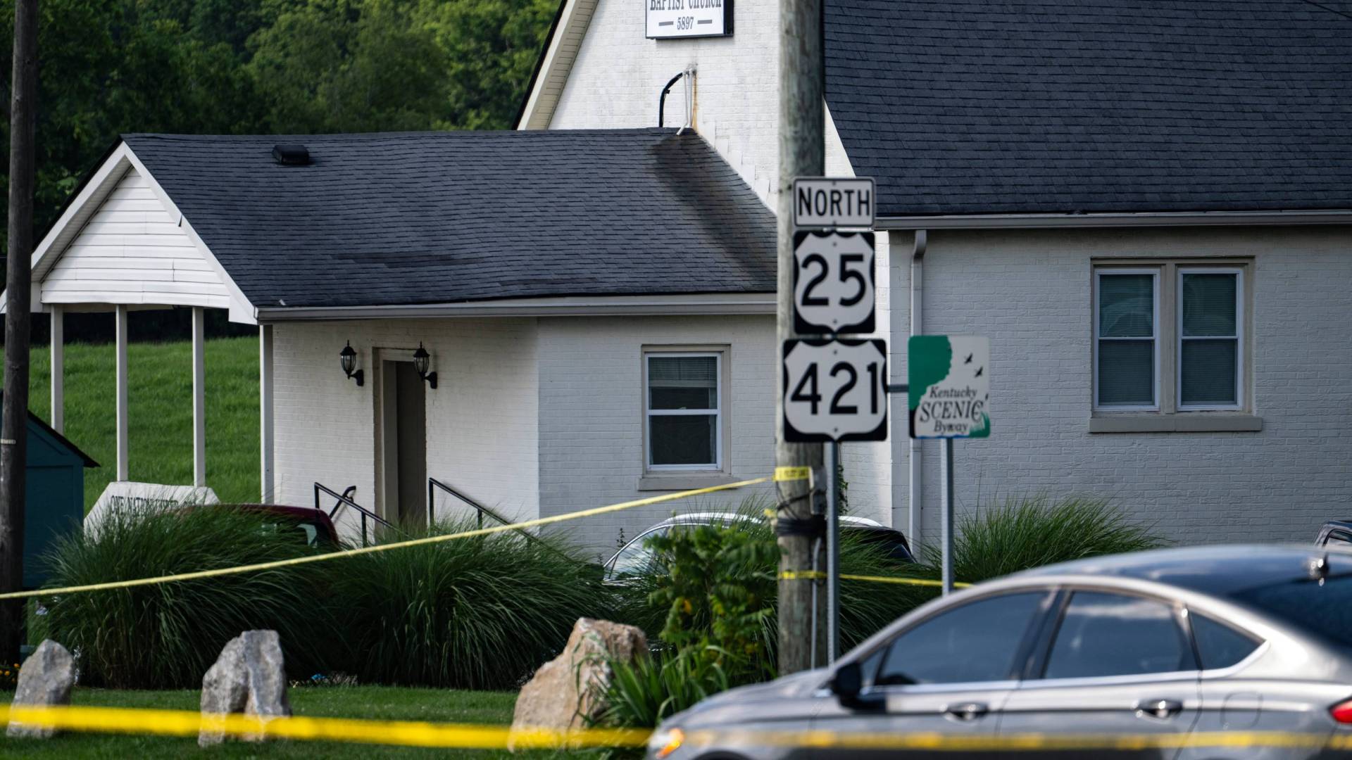 White church with grey roof surrounded by police tape adn cars.