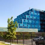 A blue windowed building surrounded by a black fence, grass, and trees with Planned Parenthood on it.