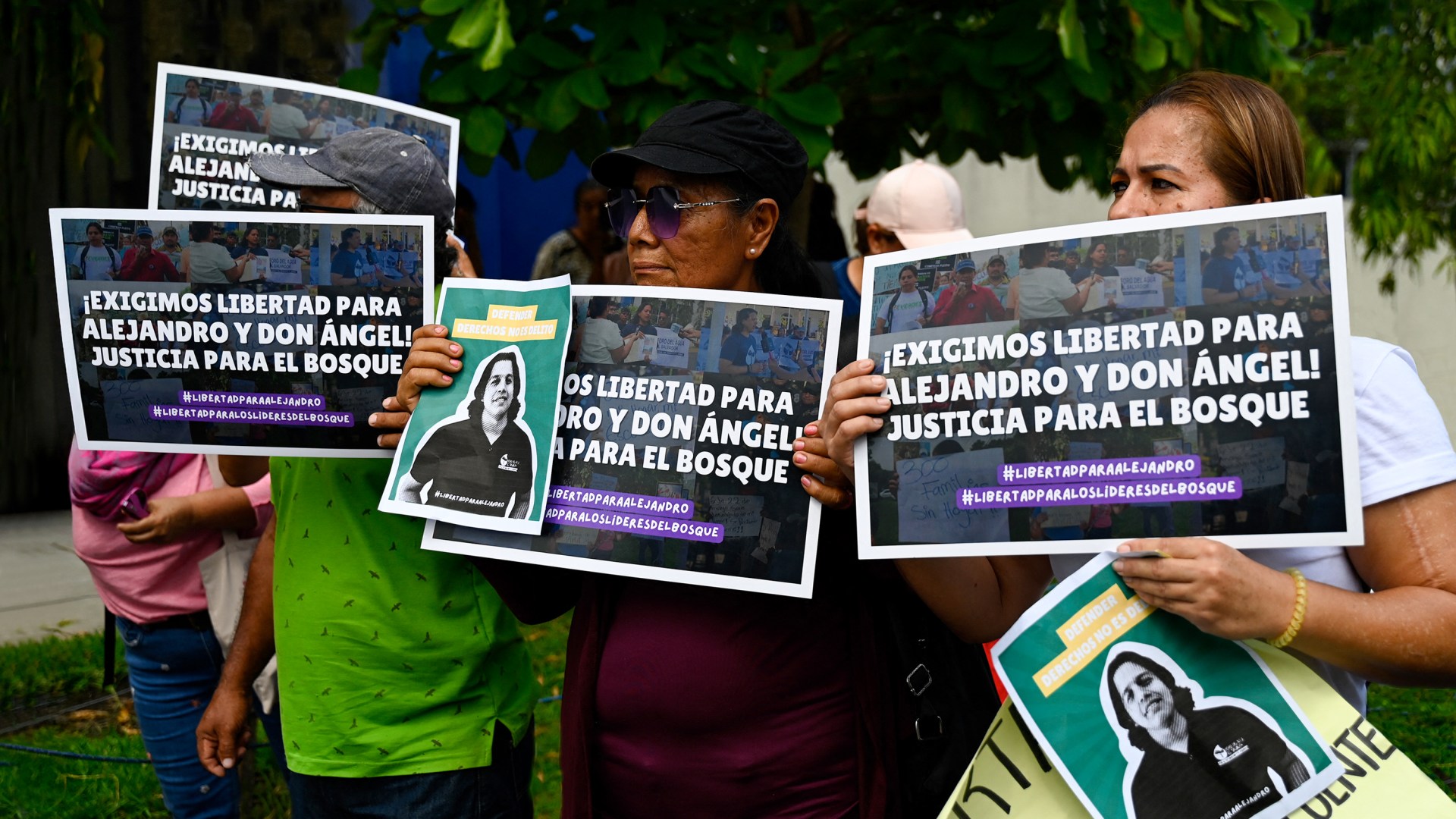 People hold signs to show their support for Salvadorian environmental lawyer activist, Alejandro Henríquez, and Pastor Jose Angel Perez who were imprisoned.
