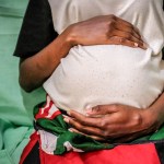 19 year old Kenyan mother is seen holding her 7 month old baby bump.