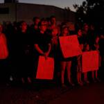 People aglow in red holding up signs in remembrance of Charlie Kirk.