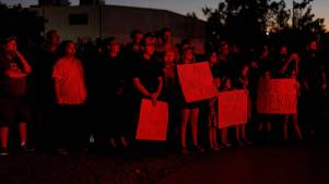 People aglow in red holding up signs in remembrance of Charlie Kirk.