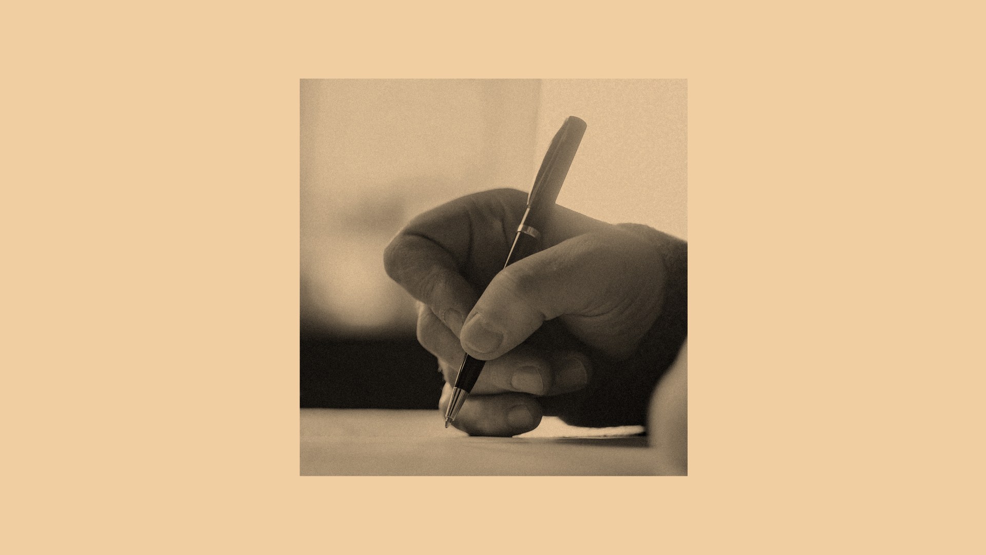 A hand writing on an orange background.