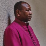 Headshot of Yassir Eric leaning against a textured wall