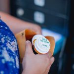 A woman holds a pill bottle in a manila envelope in a mail room.