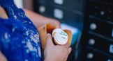 A woman holds a pill bottle in a manila envelope in a mail room.
