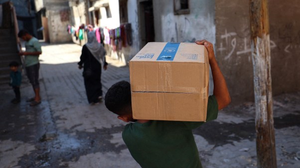 A displaced Palestinian boy carries a box of emergency supplies provided by the World Food Programme (WFP) in the Nuseirat refugee camp in Gaza on October 19, 2025.