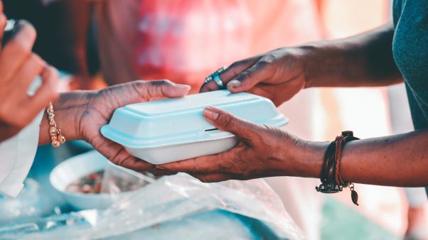 Hands pass off a styrofoam container