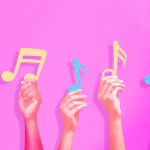 Hands holding up music notes.