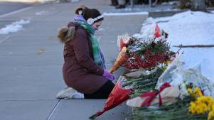 Brown University student kneels in front of a memorial