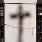 The shadow of a cross on the wall of Lebanon's Roumieh prison as prisoners stand behind bars during the Holy Thursday mass.