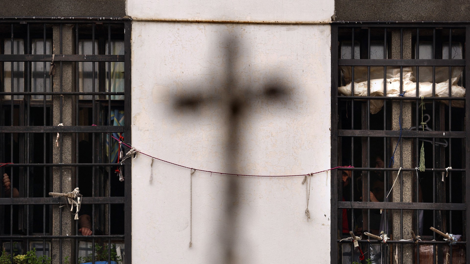 The shadow of a cross on the wall of Lebanon's Roumieh prison as prisoners stand behind bars during the Holy Thursday mass.