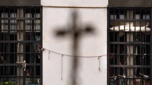 The shadow of a cross on the wall of Lebanon's Roumieh prison as prisoners stand behind bars during the Holy Thursday mass.