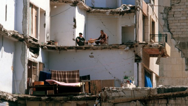 Two men sit at a table in what remains of their devastated apartment after the takeover of West Beirut by Druze militia forces.