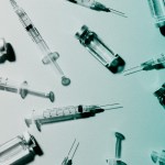 Several medical syringes and vaccine vials.