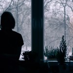 A person looking out of a snowy window.
