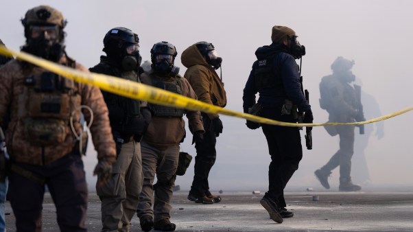 Federal agents stand in tear gas and face protesters on Nicollet Avenue in south Minneapolis on January 24, 2026.