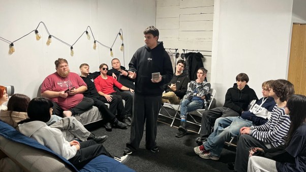 Pastor Alex Zaytsev, on the end of the couch in a red shirt, hosting his teen ministry.