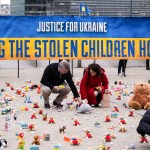 People from the nonprofit organization, AVAAZ, light candles in Belgium beside teddy bears for Ukrainian children who have been kidnapped.