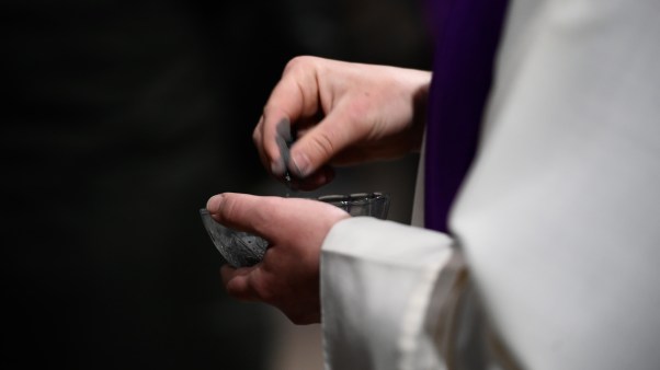A pastor holding a bowl of ashes.