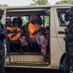 Security officers stand guard next to a bus carrying freed worshippers at the Government House in Kaduna.