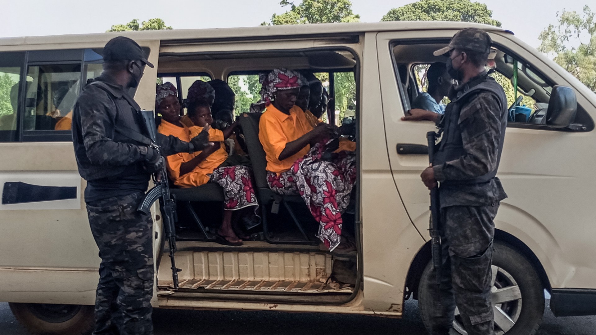 Security officers stand guard next to a bus carrying freed worshippers at the Government House in Kaduna.