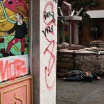 Person lying on a sidewalk in a graffiti-covered Chinatown street.
