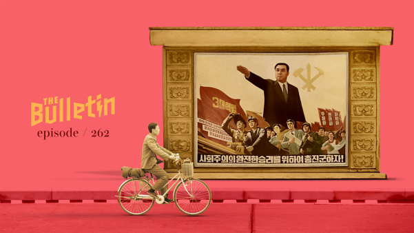 Man bikes past a communist-style propaganda poster of a North Korean leader.
