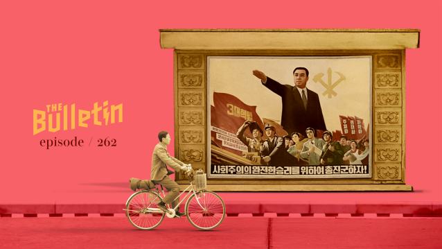 Man bikes past a communist-style propaganda poster of a North Korean leader.