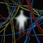 Blurred glowing human figure behind a tangle of colorful cables against a dark background.