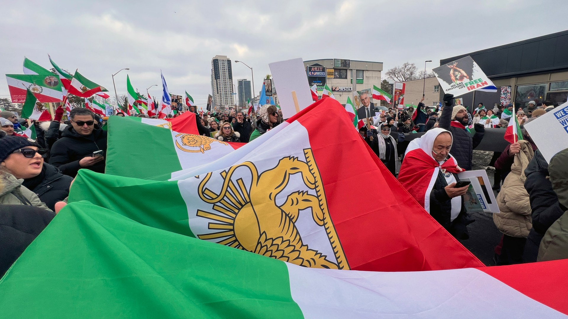 Protestors in Canada carry a large Iranian flag as part of a Global Day of Action protest against the Islamic Republic of Iran on February 14, 2026.