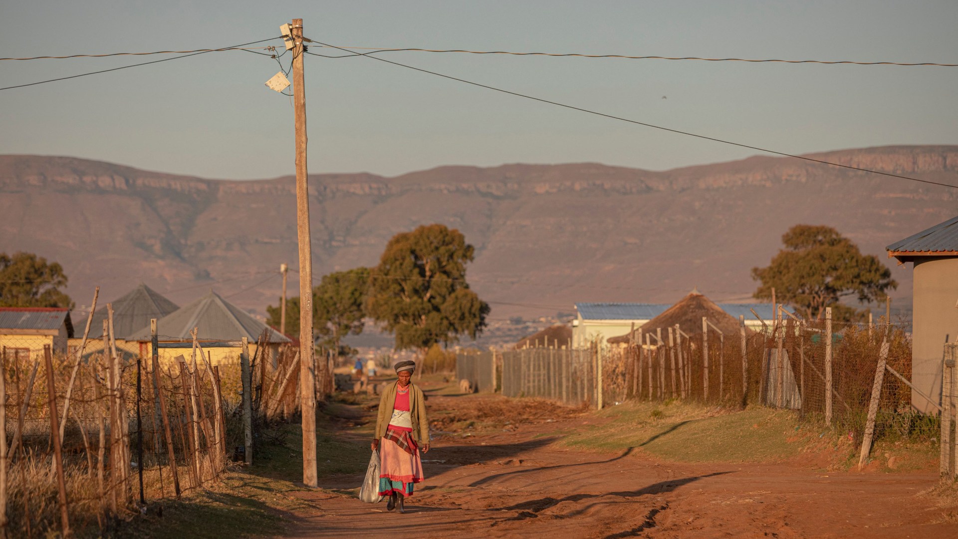 A woman walking on a dirt road in Zingqolweni village in South Africa.