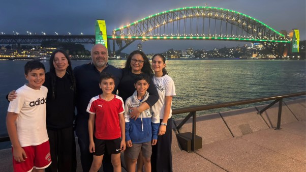 The Elachi family at the Sydney Harbour Bridge on December 10, 2025, the day of the social media ban. The sign on the bridge behind them reads, "Let Them Be Kids."